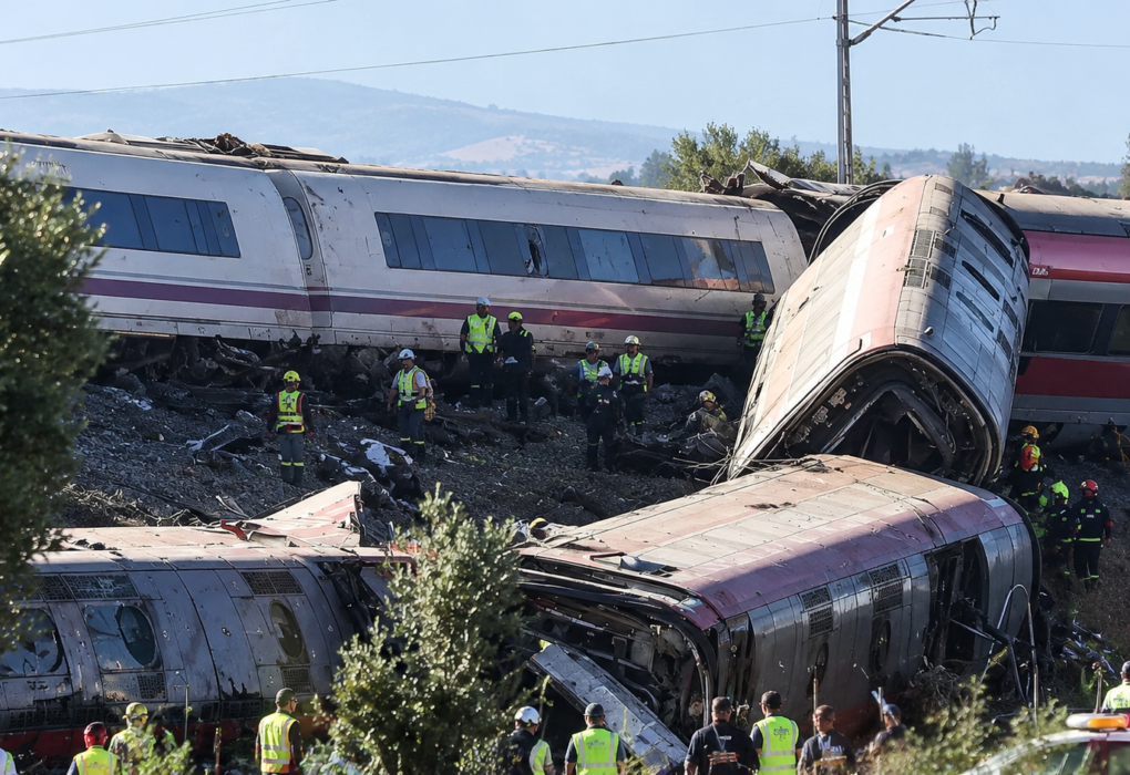 Derailment of passenger trains in Spain with damaged train carriages and emergency crews working at the crash site.