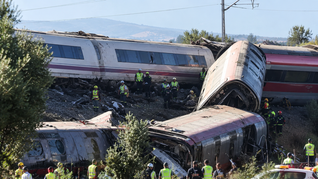 Derailment of passenger trains in Spain with damaged train carriages and emergency crews working at the crash site.