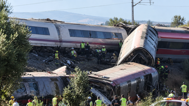 Derailment of passenger trains in Spain with damaged train carriages and emergency crews working at the crash site.